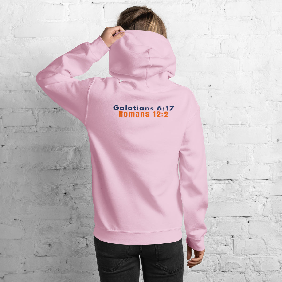 Back of Model wearing Gildan 18500 heavy blend hooded sweatshirt in Light Pink, showing a classic fit and Printed on the back is the Marked & Chosen Verses: Galatians 6:17 and Romans 12:2.
